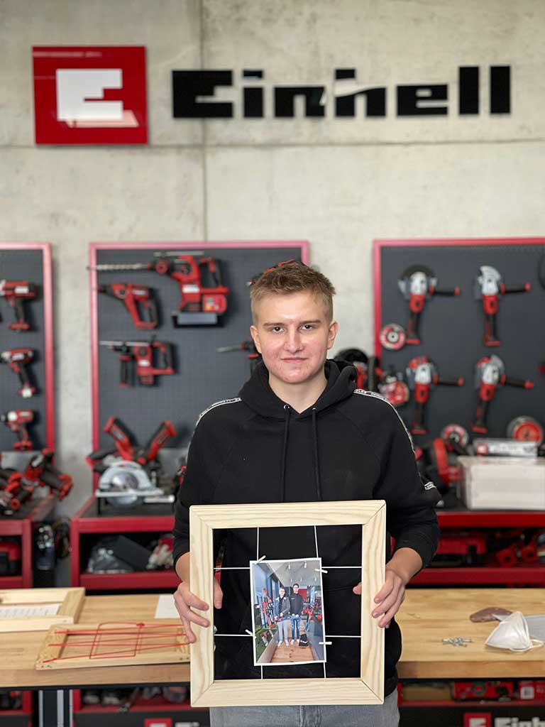 trainee holds wooden frame with a photo of himself and his godfather