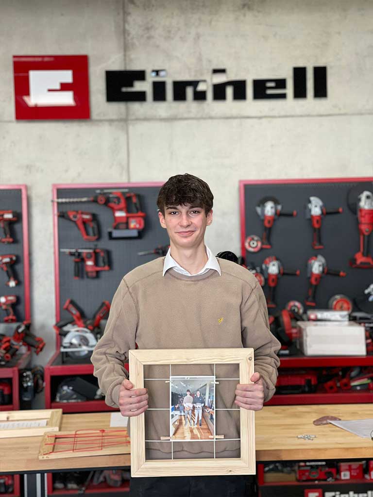 trainee holds wooden frame with a photo of himself and his godfather