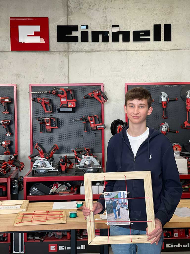 trainee holds wooden frame with a photo of himself and his godfather