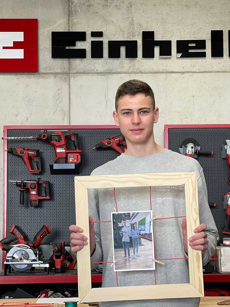 trainee holds wooden frame with a photo of himself and his godfather
