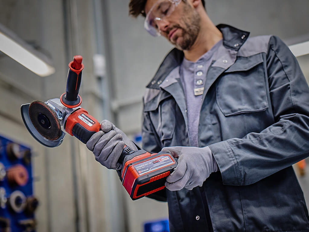 A man putting a Power X-Change battery into an Einhell angle grinder.