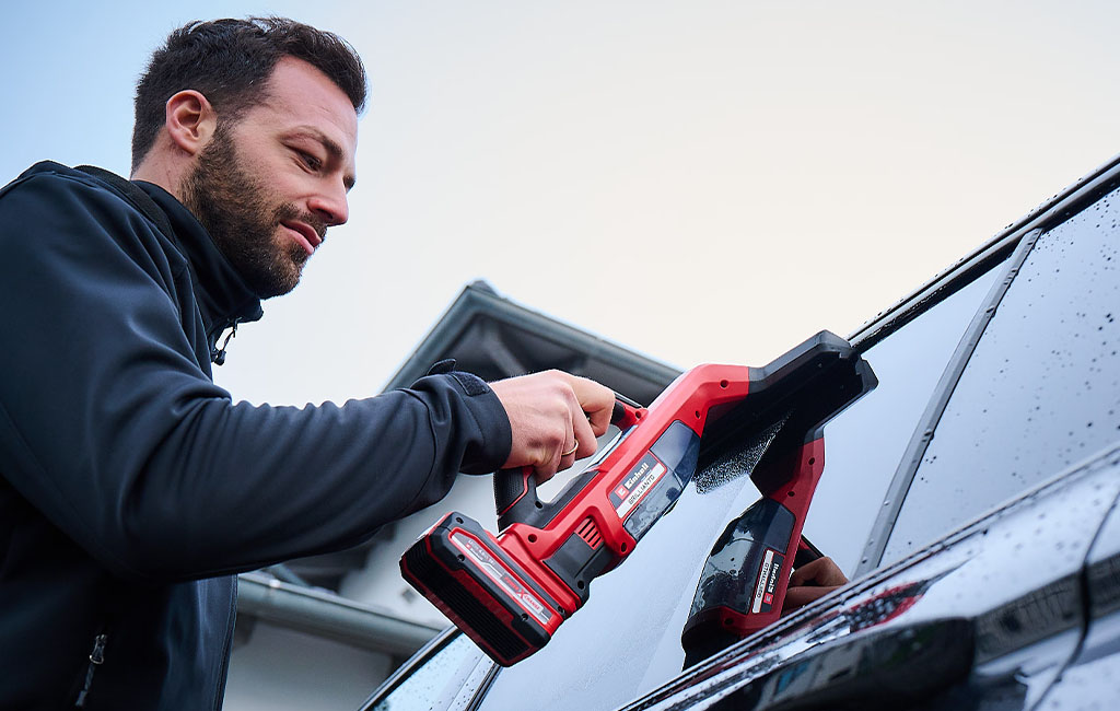 ein Mann reinigt die Fenster eines Autos mit dem Einhell BRILLIANTO