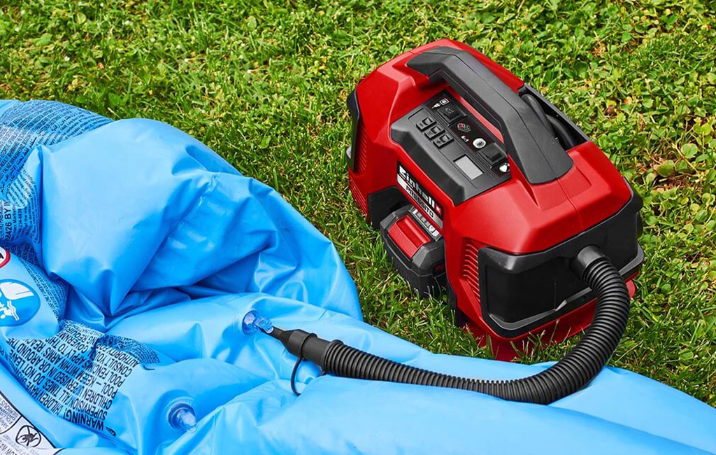 The Einhell PRESSITO cordless compressor is used to inflate an air mattress on the lawn.