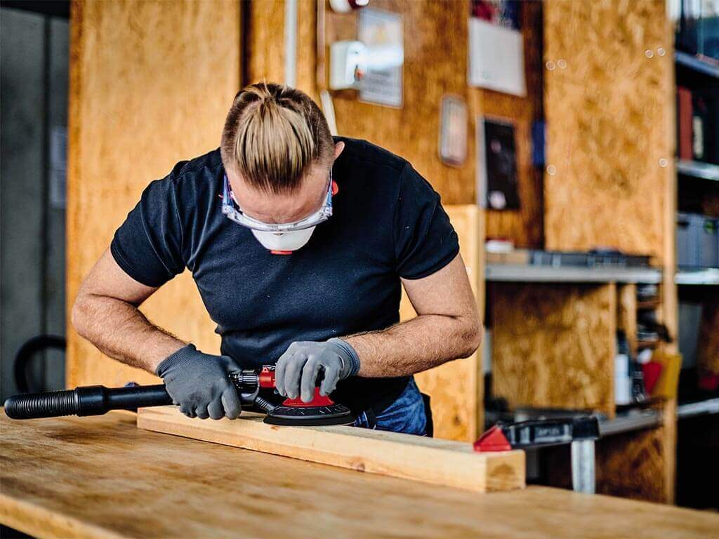 a man grinds down a wooden board