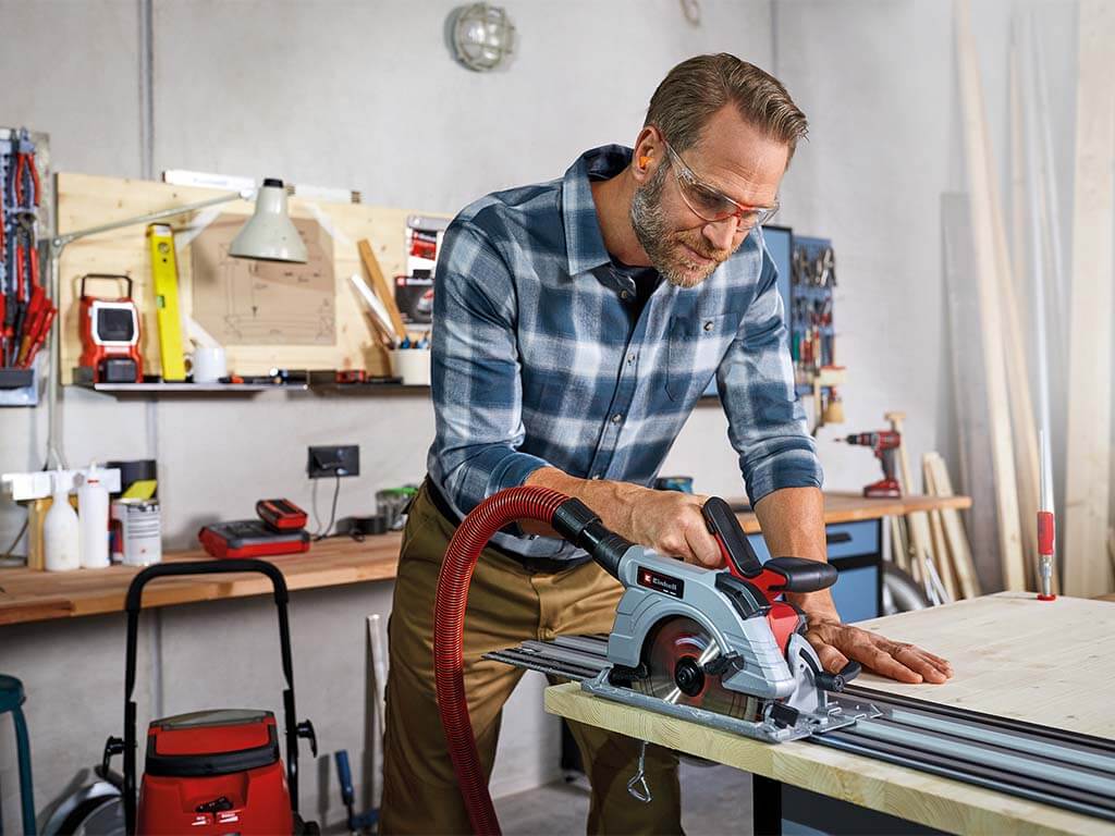 a man cuts wood on a workbench with a hand circular saw