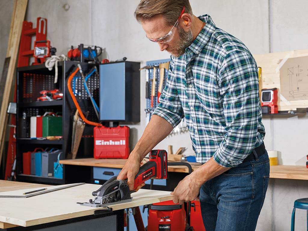 a man cuts wood with a hand circular saw