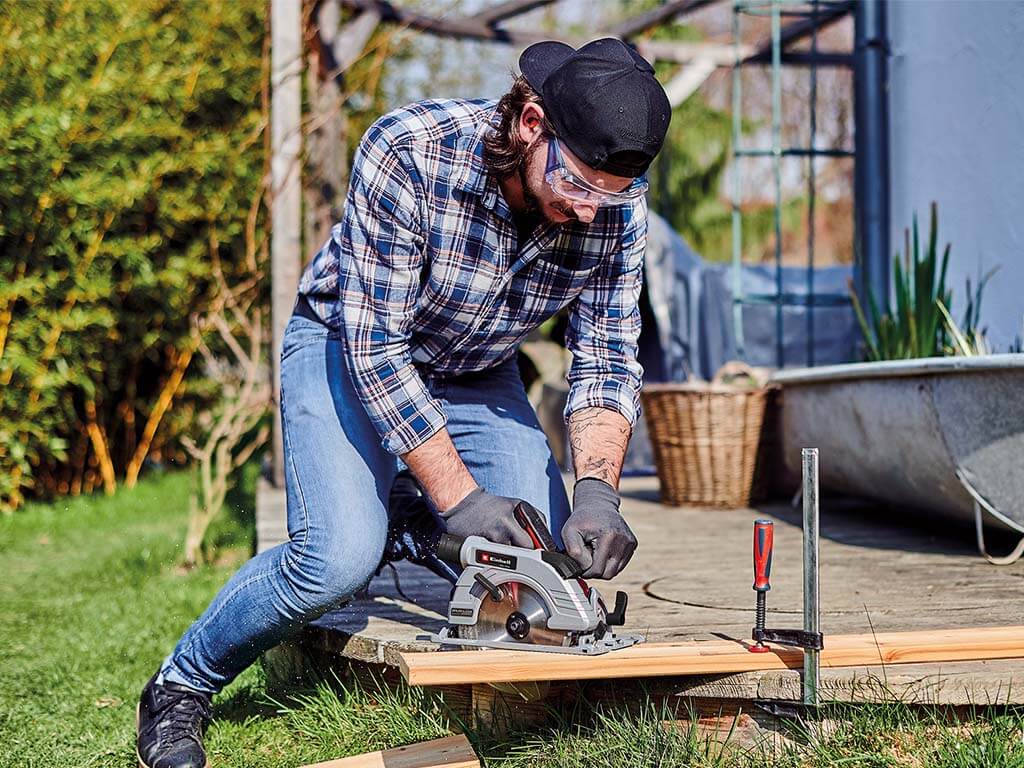 man cuts wood piece with hand circular saw