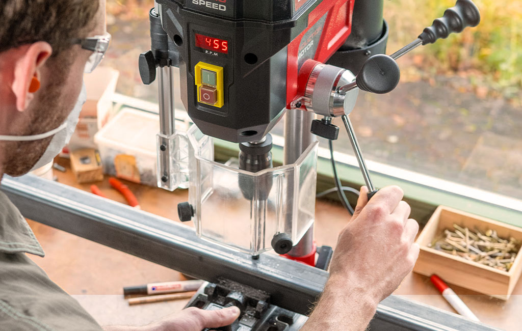Einhell pillar drill drilling a hole into a clamped metal profile.