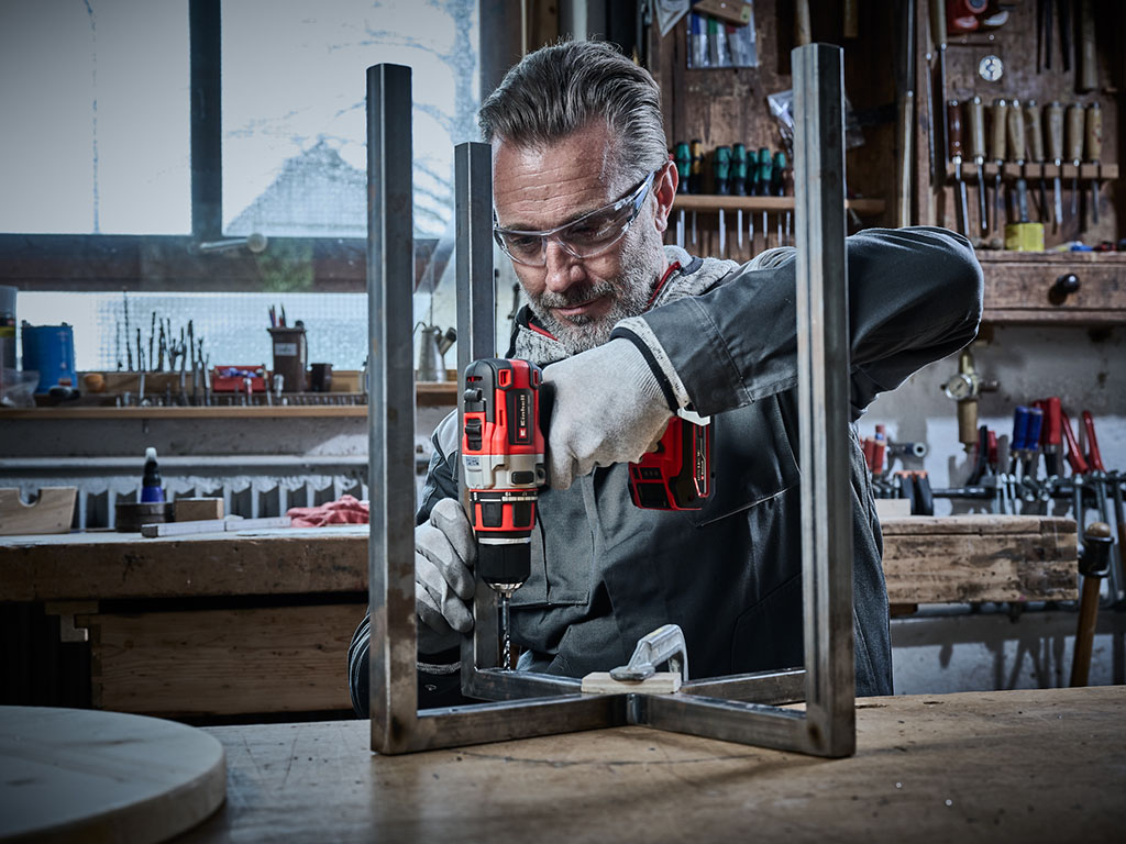 Handwerker bohrt mit einer Einhell Bohrmaschine ein Loch in ein Metallprofil.
