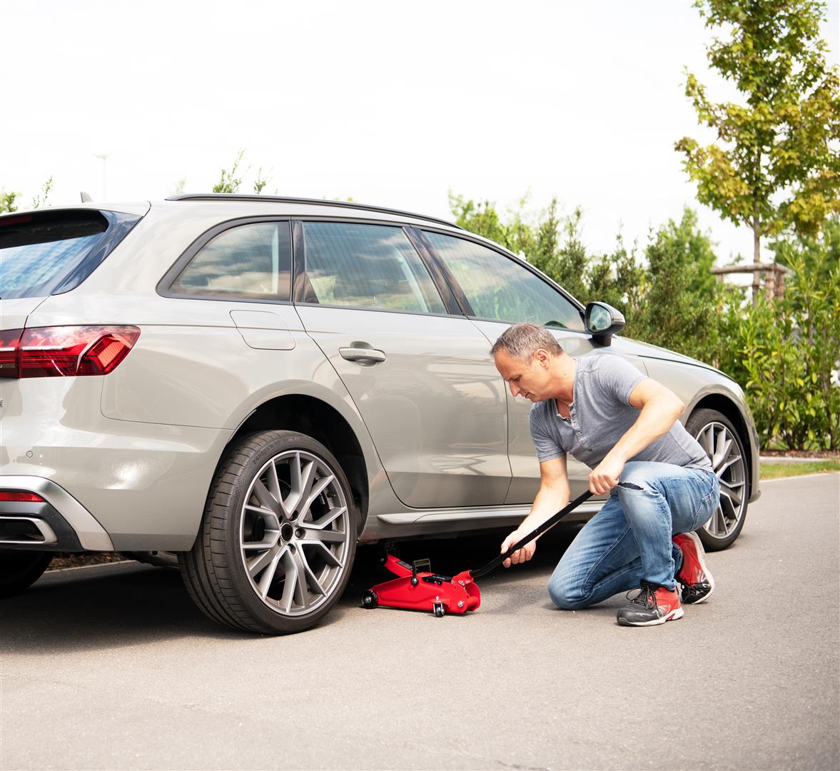 a man lifts his car to change tires