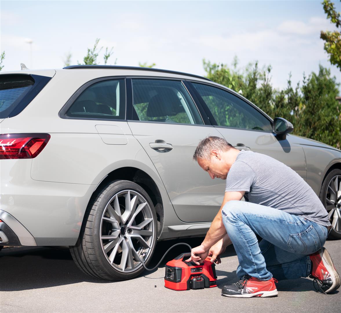 a man inflates his car tire with a compressor