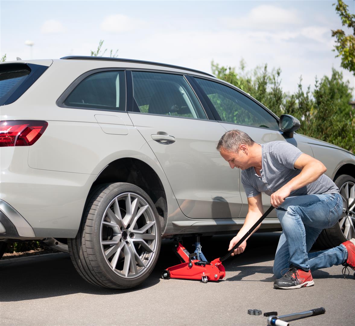 a man lifts his car to change a tire