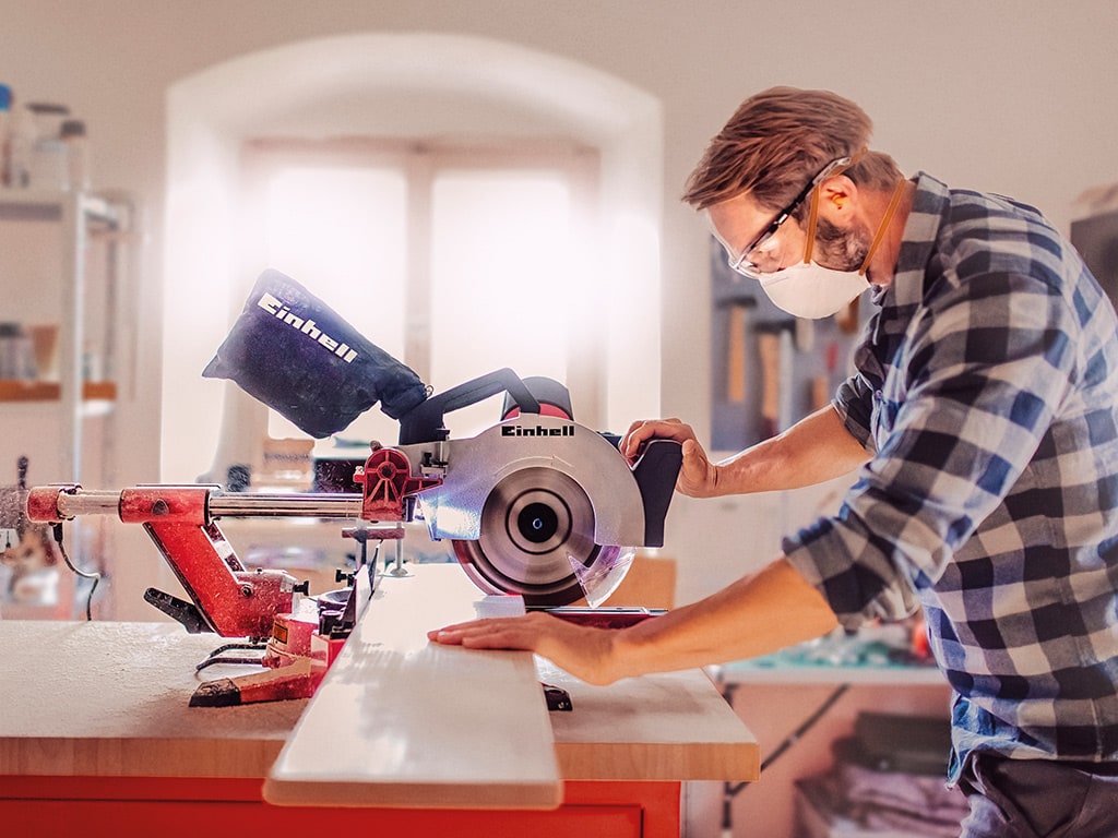 a man cuts a wooden board with a table saw