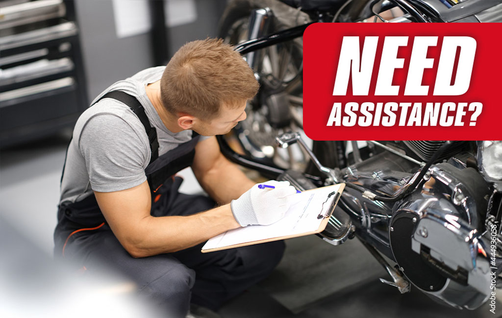 Person inspecting a motorcycle in a workshop with a checklist in hand, text in image: “Help needed?”