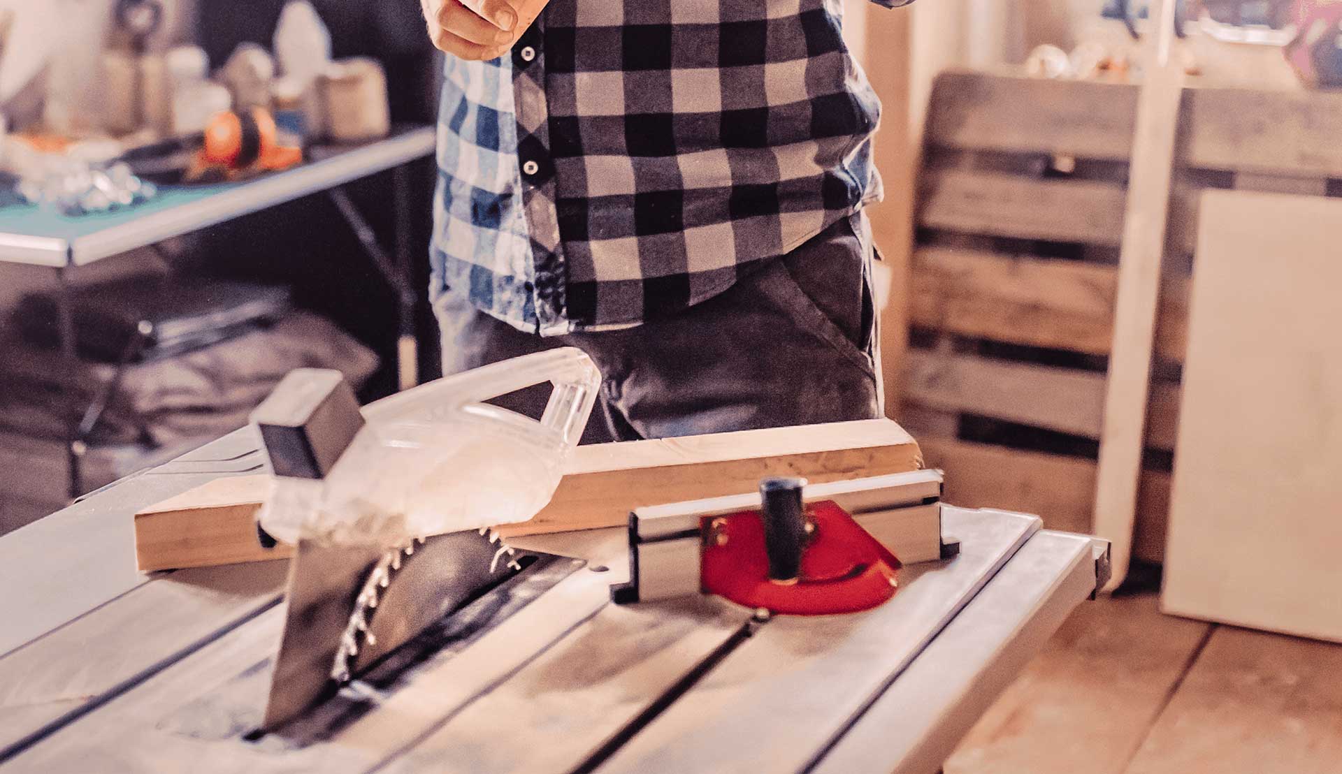 Ein Mann nutzt einen Winkelanschlag auf einer Tischkreissäge, um eine Holzlatte im richtigen Winkel zu sägen.