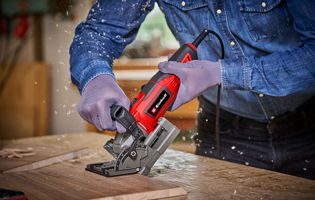 Close-up of a cordless Einhell biscuit joiner cutting a slot into a wooden board.