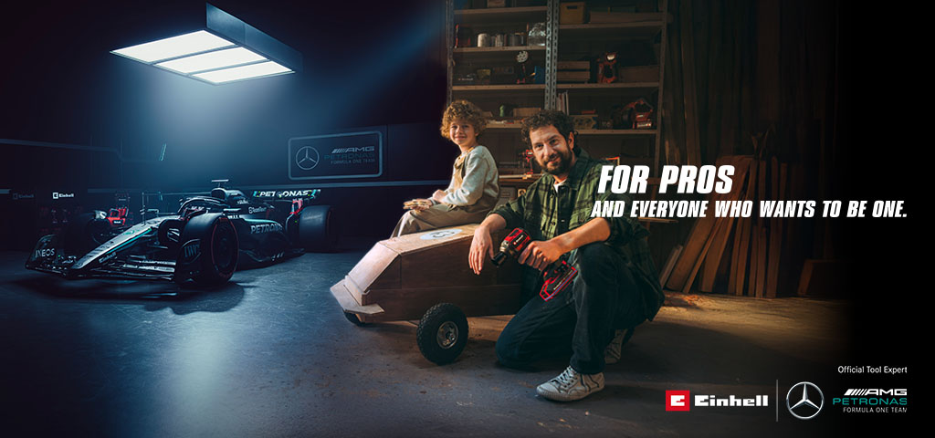 A father and child in a workshop with a homemade soapbox car. In the background, a Mercedes-AMG PETRONAS Formula One car and Einhell tools. Text on the right reads: "For professionals and those who want to become one."