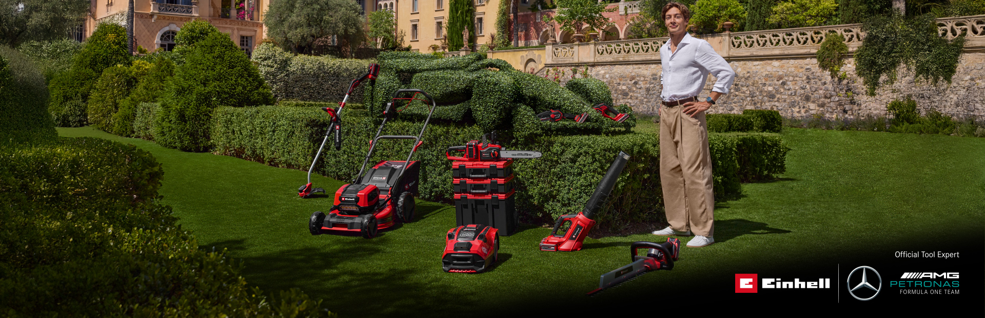 George Russell stands in a Mediterranean garden with Einhell cordless garden tools. Next to him, a race car-shaped hedge. Bottom right: Einhell and Mercedes-AMG PETRONAS F1 Team logos.