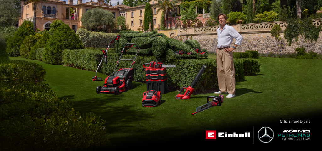George Russell stands in a Mediterranean garden with Einhell cordless garden tools. Next to him, a race car-shaped hedge. Bottom right: Einhell and Mercedes-AMG PETRONAS F1 Team logos.