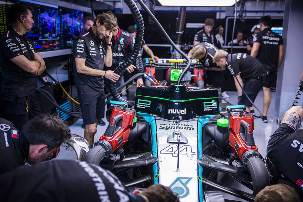 The Formula 1 Mercedes Team standing around the race car. 