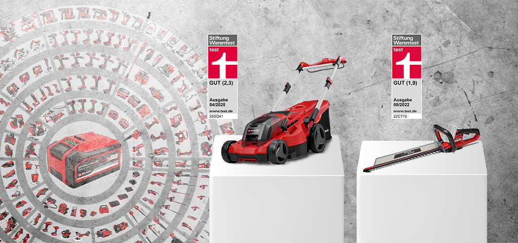 An Einhell cordless lawn mower and cordless hedge trimmer on white pedestals in front of a concrete wall. To the left, a Power X-Change battery with icons of compatible tools. The lawn mower was rated GOOD (2.3) by Stiftung Warentest, issue 04/2025. The hedge trimmer was rated GOOD (1.9), issue 08/2022.