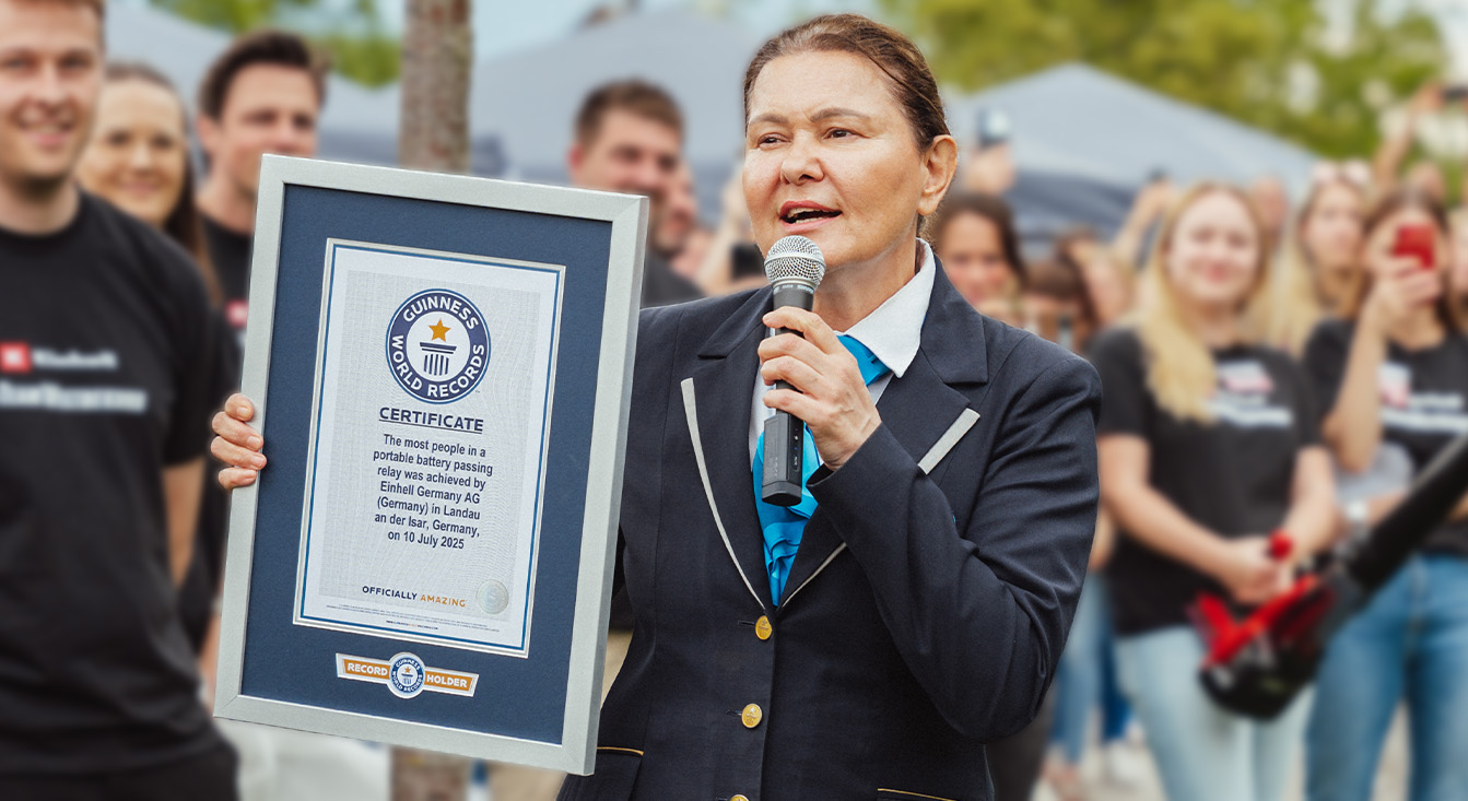Eine Frau im offiziellen Guinness-Outfit hält eine Urkunde für den Weltrekord im Akku-Staffellauf von Einhell.