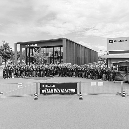 Schwarz-weiß Foto: Das Guinness World Records Logo über einem Event-Foto mit Einhell-Werkzeugen.