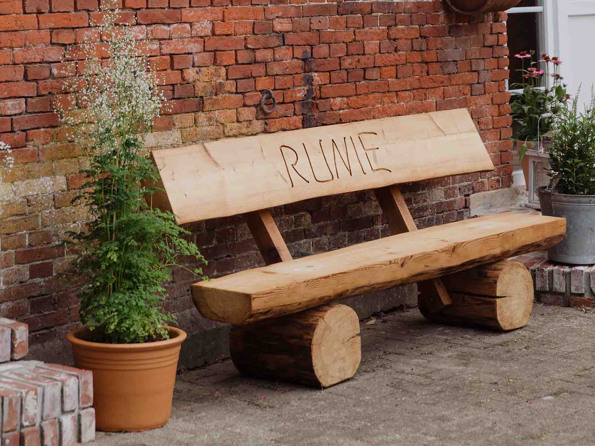 Homemade wooden bench made from a tree trunk with runic inscription on the back