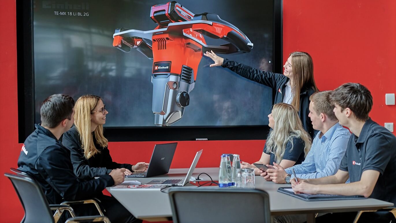 A group of people sitting in a meeting room and listening to a presentation of an Einhell product.