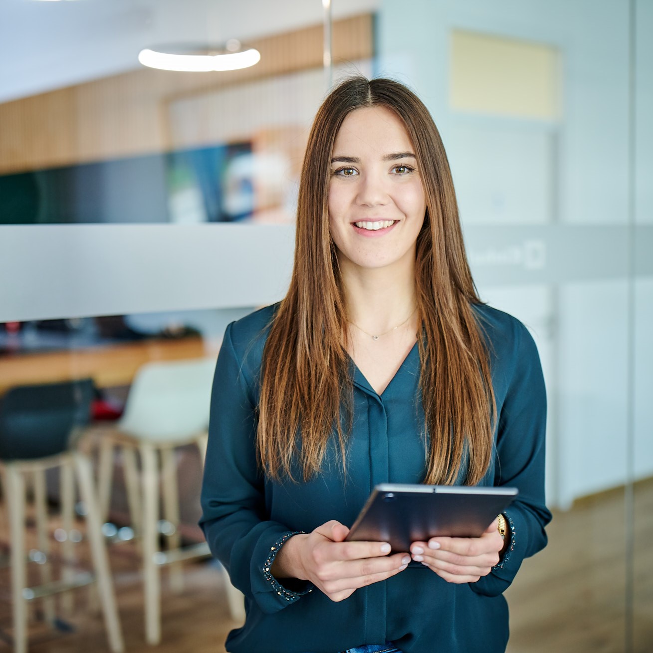 A woman holding an ipad and smiling into the camera.