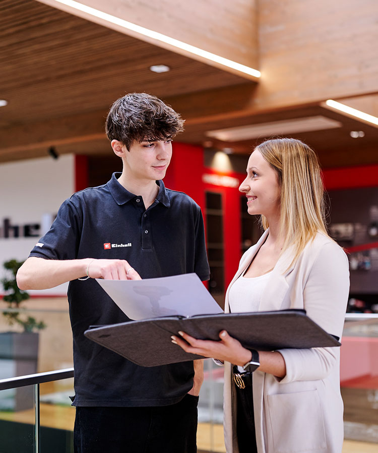 a woman and a man look at a cordless drill on a piece of paper