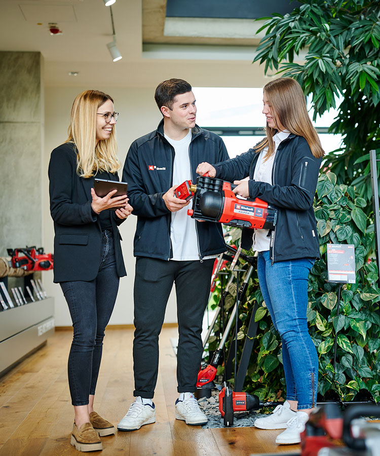 two woman and a man take a closer look at a water pump