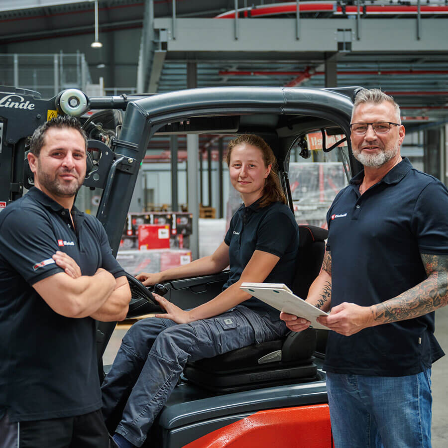 a woman sits on a forklift and two men stand next to her