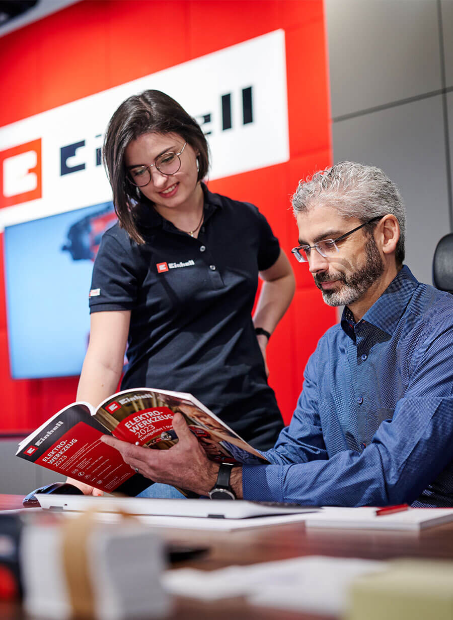 A woman and a man looking into the Einhell catalog.