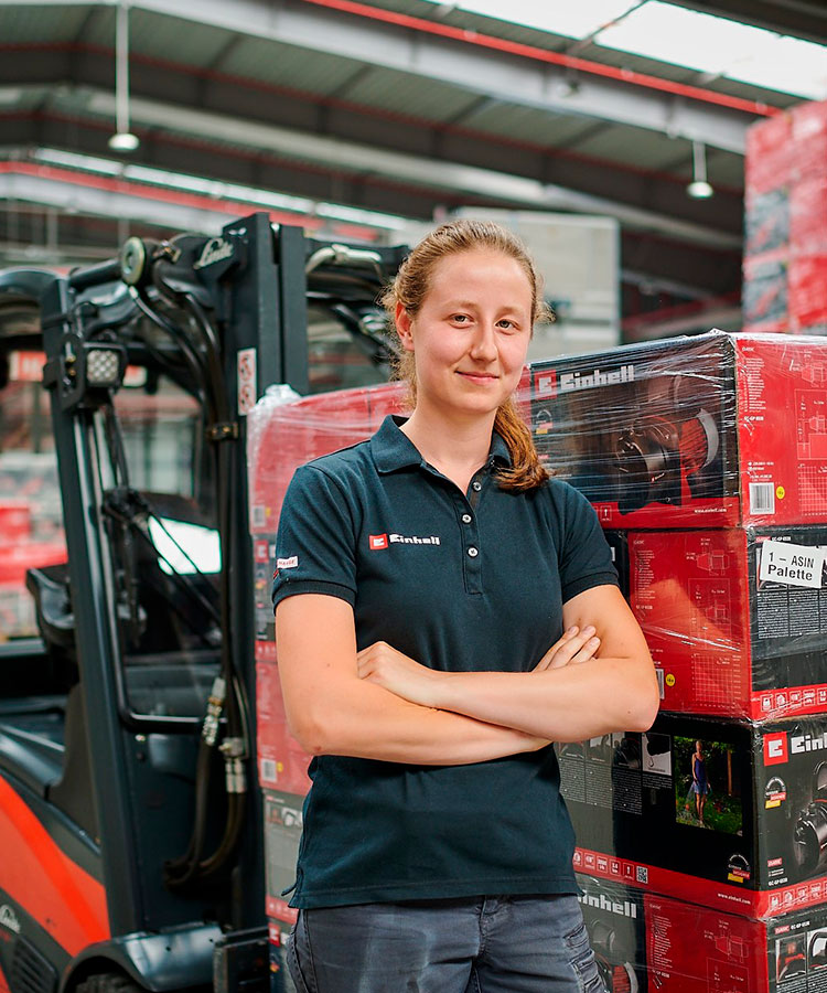 A woman standing in the warehouse next to Einhell packages.