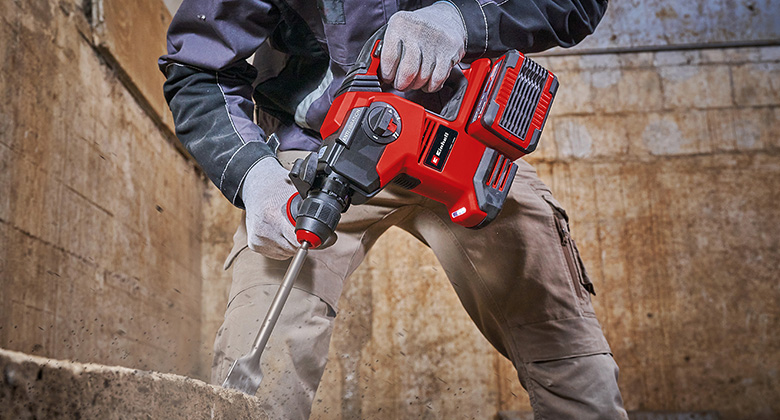 Ein Handwerker benutzt einen Einhell Akku-Bohrhammer, um mit einem Meißelaufsatz Beton zu bearbeiten.