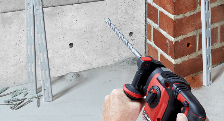 Ein Einhell Bohrhammer wird verwendet, um Löcher in eine Betonwand und eine Backsteinmauer zu bohren.
