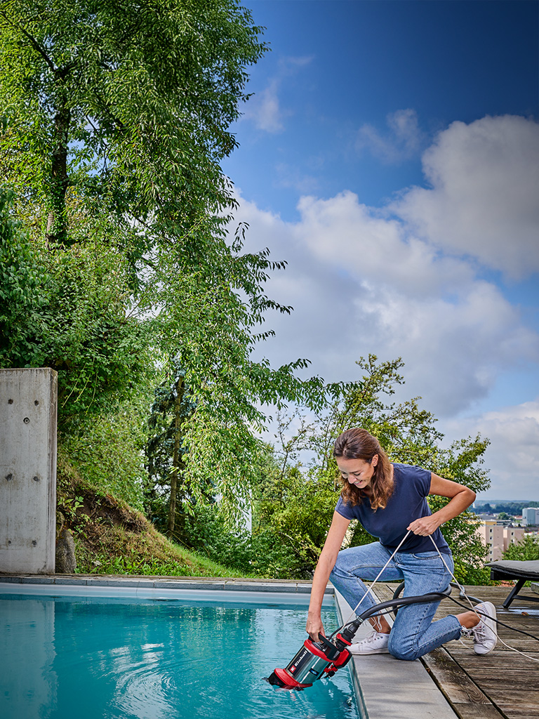 Eine Frau nutzt eine Klarwasserpumpe, um einen Pool auszupumpen.