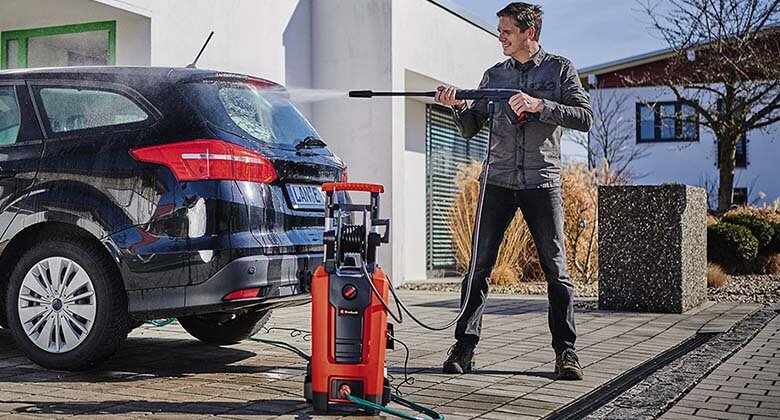 Mann reinigt ein dunkles Auto mit einem Einhell Hochdruckreiniger