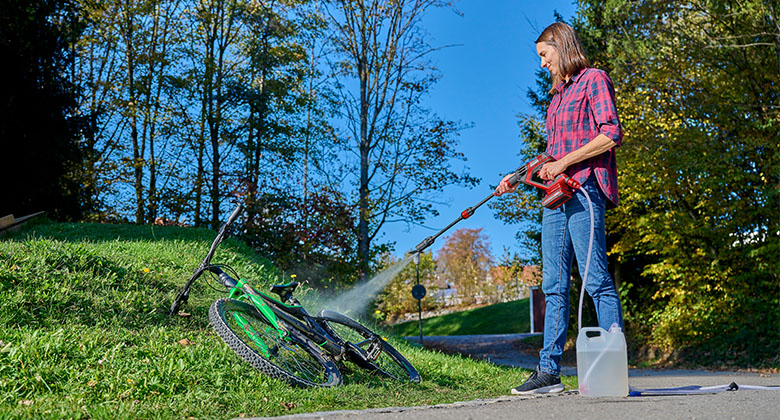 Frau reinigt ihr Fahrrad mit dem Einhell HYPRESSO Akku-Druckreiniger