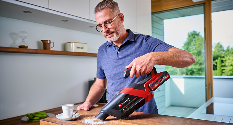 Mann saugt Zucker von Künchenoberfläche mit dem Einhell Akku-Handstaubsauger