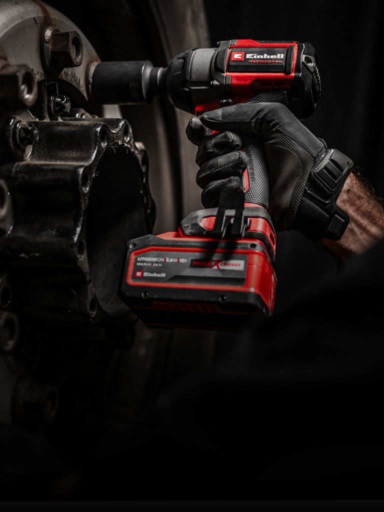 Close-up of a red cordless impact wrench being used on a wheel