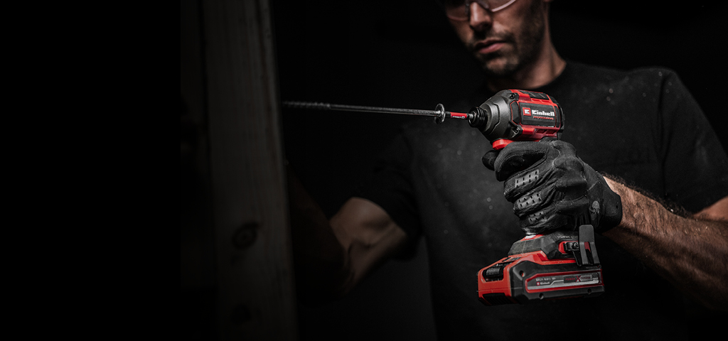 The banner shows a man tightening a screw with an Einhell cordless impact driver. The background is dark, with the focus on the tool.