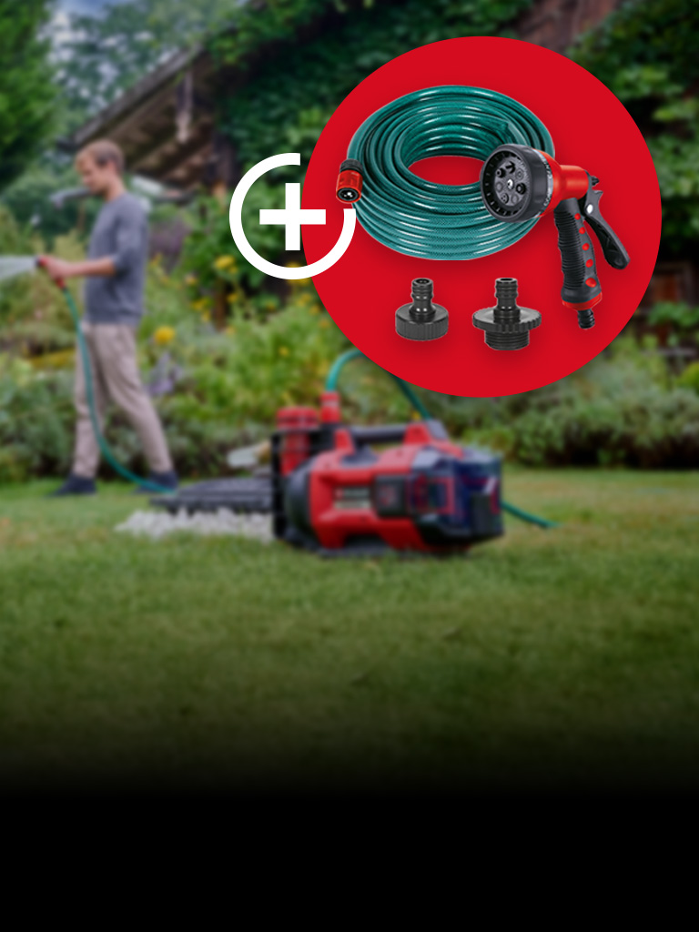 Eine Person bewässert einen Garten mit einem Gartenschlauch, während im Vordergrund eine rot-schwarze Wasserpumpe auf dem Rasen steht. Im roten Kreis befinden sich ein aufgerollter Gartenschlauch, eine Sprühpistole sowie zwei Anschlussadapter als Zubehör.