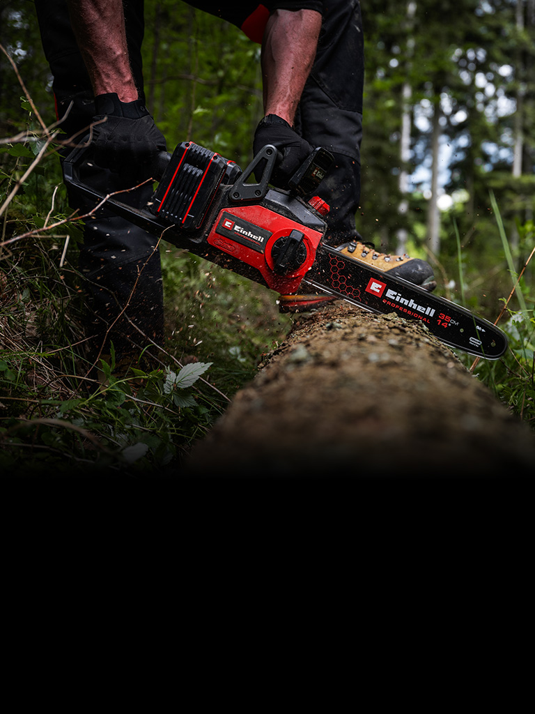 ChatGPT said: A person is using a red-and-black cordless chainsaw to cut through a fallen tree in a dense forest. The scene shows wood chips flying as the saw cuts into the trunk.
