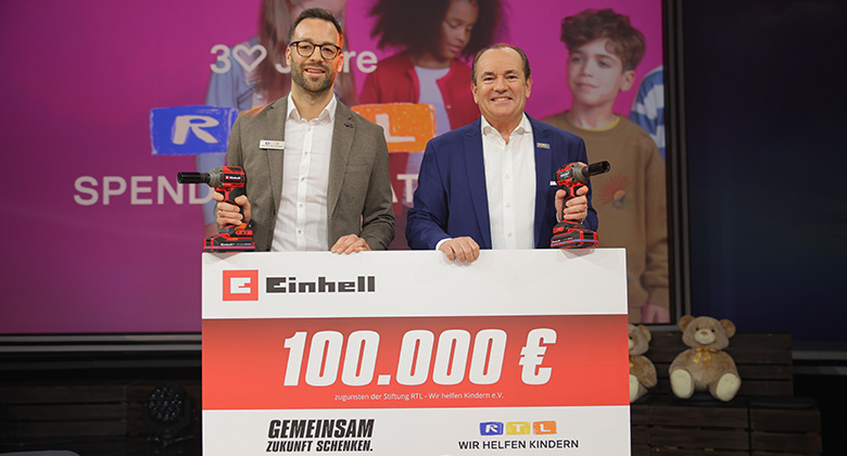 Zwei Männer halten je einen Einhell Akkubohrschrauber und präsentieren einen Spendenscheck über 100.000 € für RTL – Wir helfen Kindern.