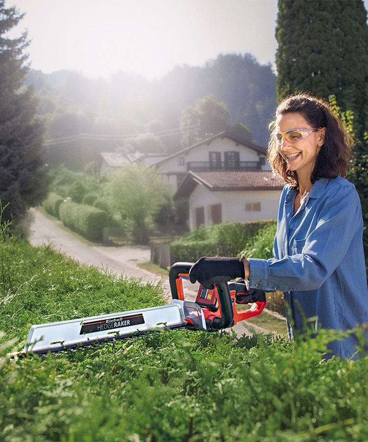 woman working with a cordless hedge trimmer