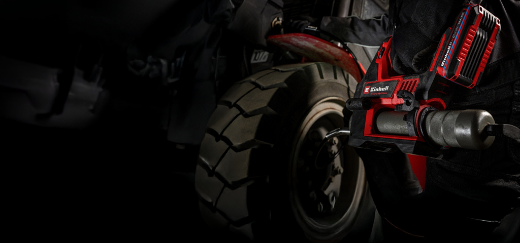 Person nutzt eine Einhell Akku-Fettpresse zur Schmierung eines Fahrzeugteils.