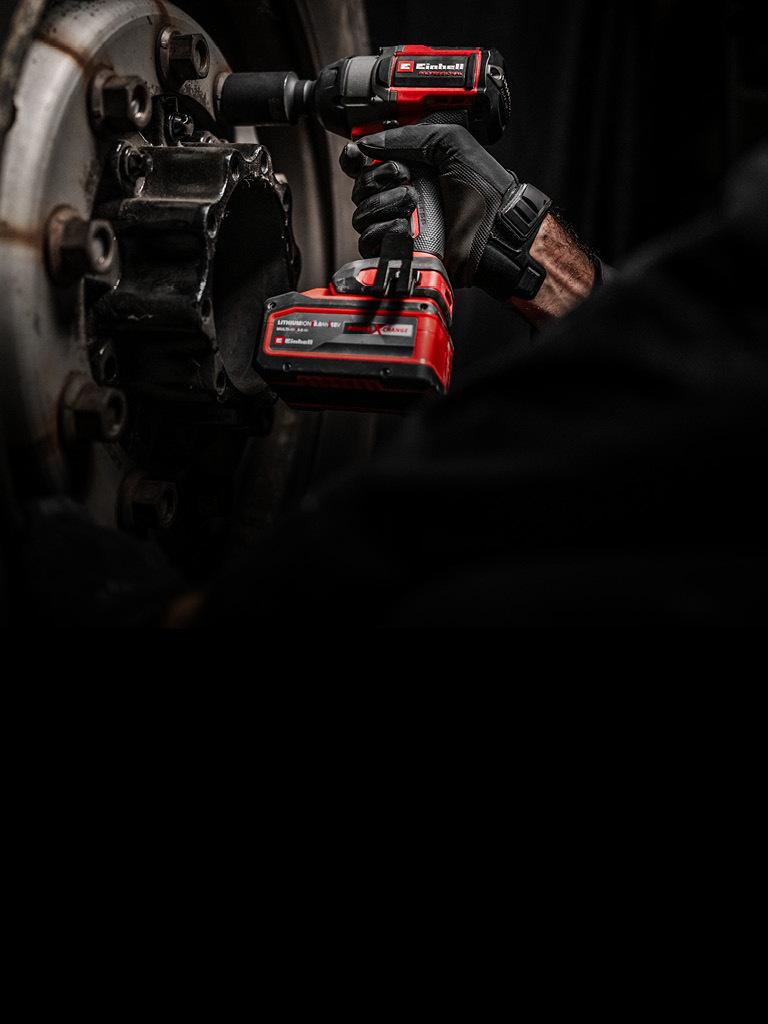 Mechaniker nutzt einen roten Einhell Akkuschlagschrauber, um eine Radschraube zu lösen.