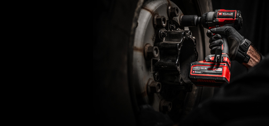 Mechaniker nutzt einen roten Einhell Akkuschlagschrauber, um eine Radschraube zu lösen.